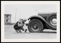 Fotografía en blanco y negro de una mujer cambiando un neumático de un coche clásico.-2