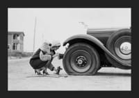Fotografía en blanco y negro de una mujer cambiando un neumático de un coche clásico.-5