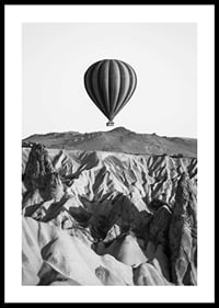 Black and white photograph of hot air balloon over dramatic landscape-0