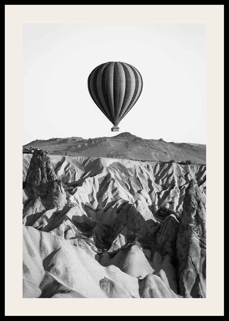 Zwart-witfoto van een heteluchtballon boven een dramatisch landschap-12