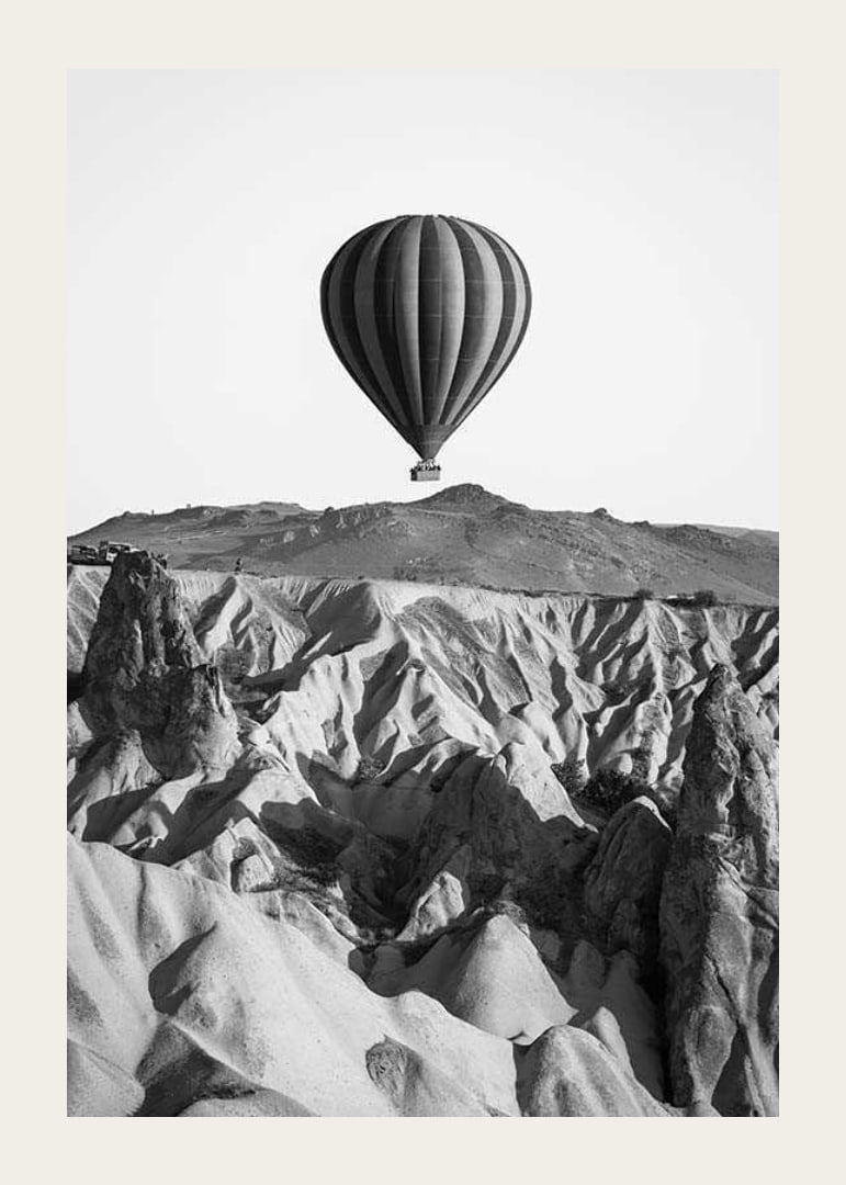 Black and white photograph of hot air balloon over dramatic landscape-12