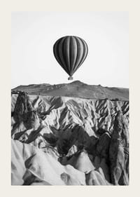 Zwart-witfoto van een heteluchtballon boven een dramatisch landschap-3