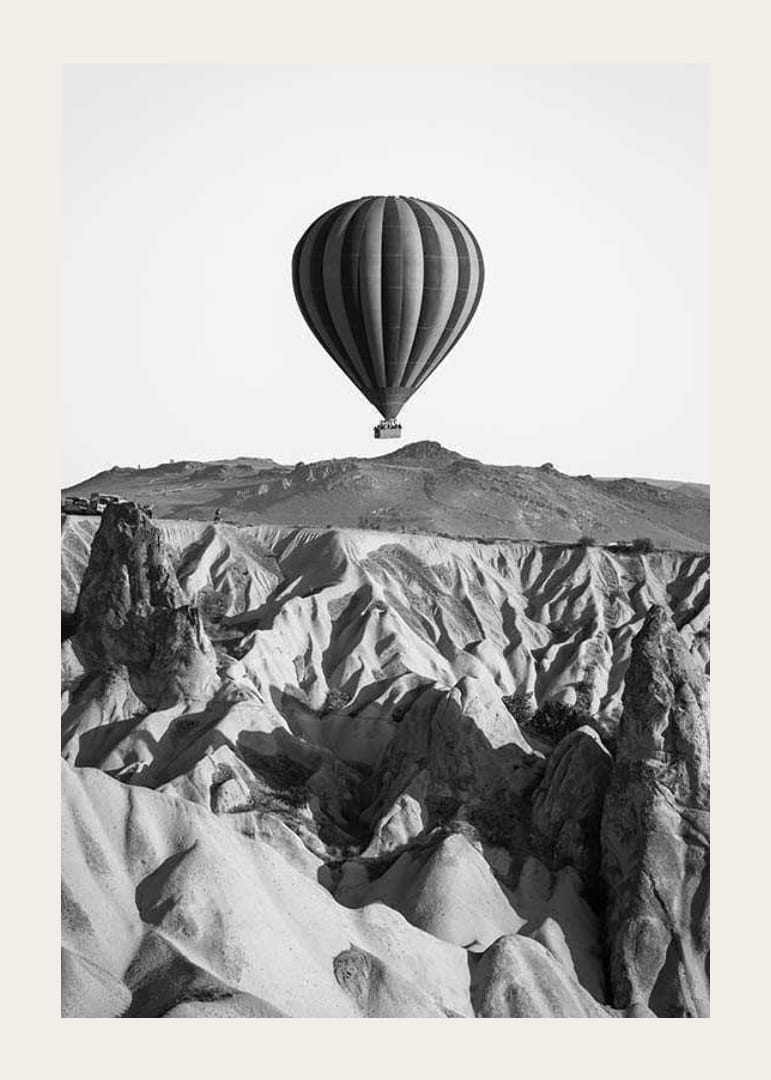 Zwart-witfoto van een heteluchtballon boven een dramatisch landschap-12