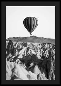 Zwart-witfoto van een heteluchtballon boven een dramatisch landschap-4