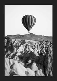Zwart-witfoto van een heteluchtballon boven een dramatisch landschap-5
