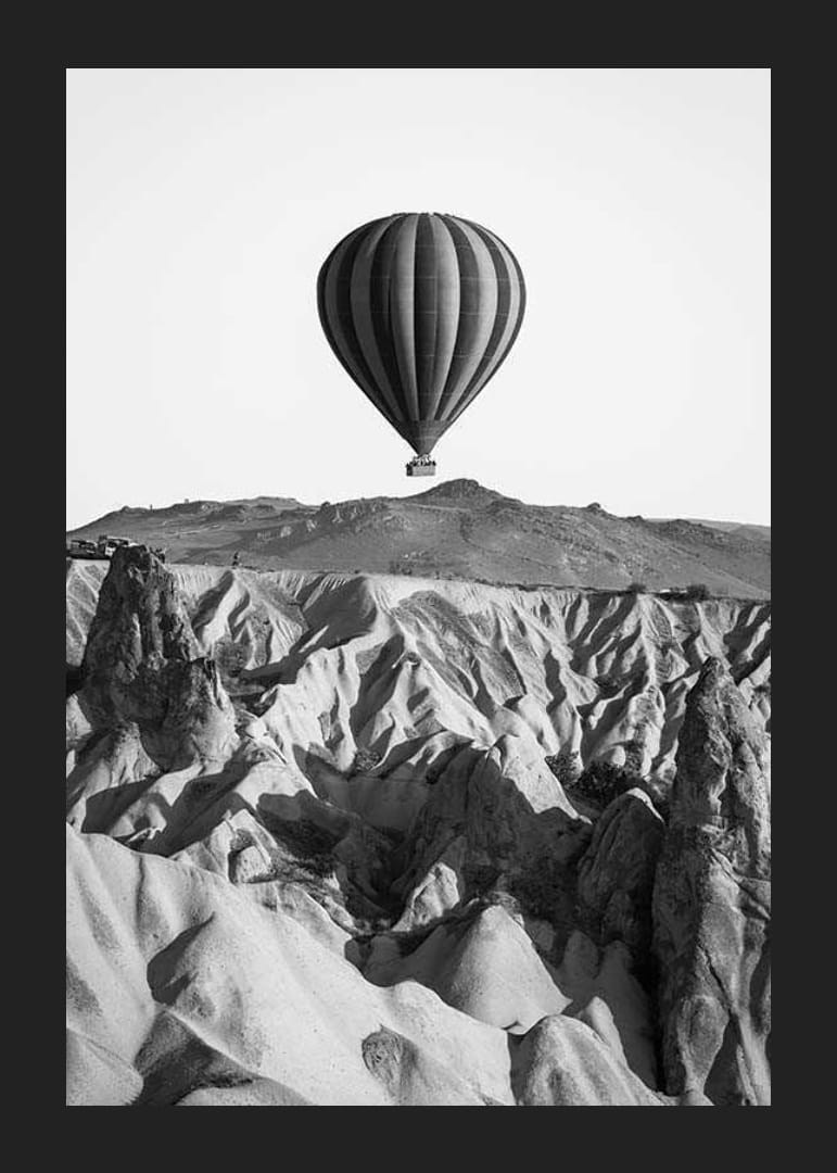 Zwart-witfoto van een heteluchtballon boven een dramatisch landschap-12