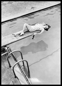 Black and white photograph of woman on trampoline above pool-6