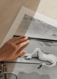 Black and white photograph of woman on trampoline above pool-9