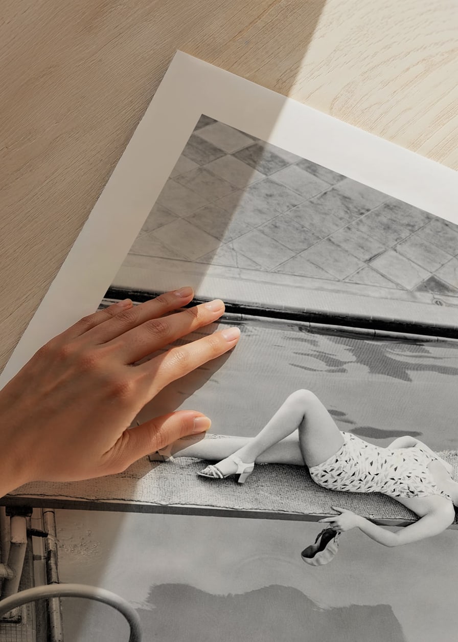 Black and white photograph of woman on trampoline above pool-12