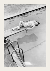 Black and white photograph of woman on trampoline above pool-3