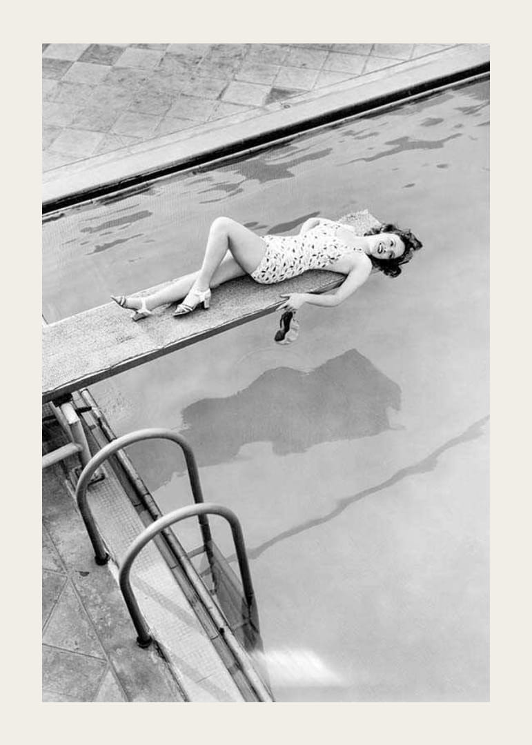 Fotografía en blanco y negro de una mujer en un trampolín sobre una piscina.-12
