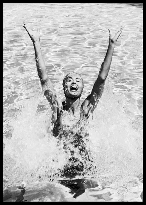 Black and white photo of smiling woman splashing water in pool-12