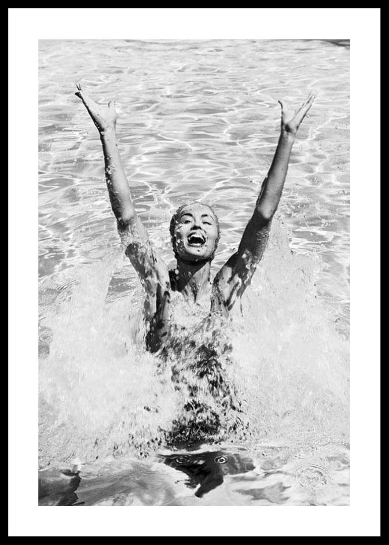 Black and white photo of smiling woman splashing water in pool-12