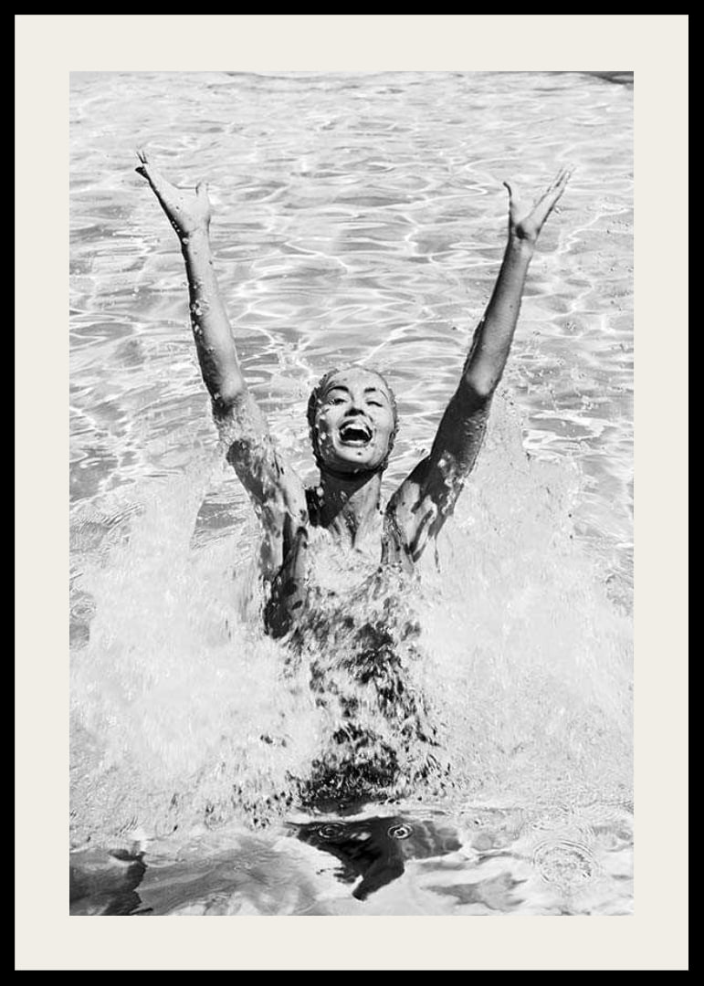 Black and white photo of smiling woman splashing water in pool-12