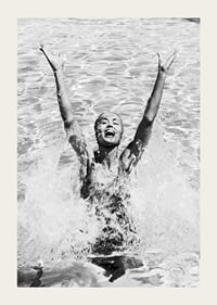 Black and white photo of smiling woman splashing water in pool-3