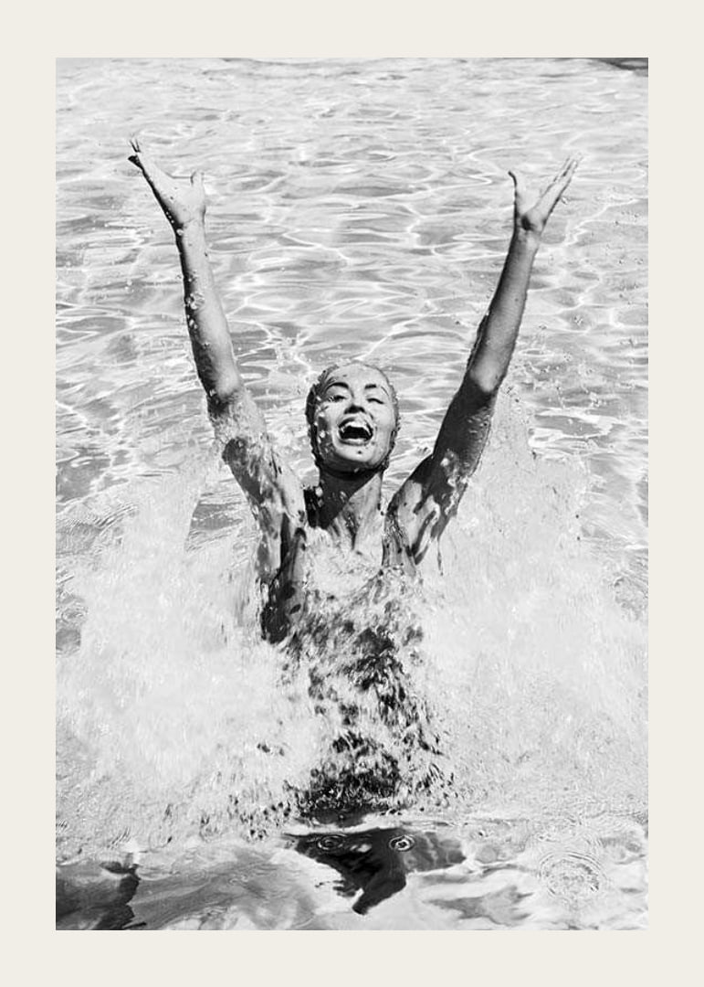 Black and white photo of smiling woman splashing water in pool-12