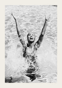 Schwarz-Weiß-Foto einer lächelnden Frau, die im Pool Wasser planscht-3