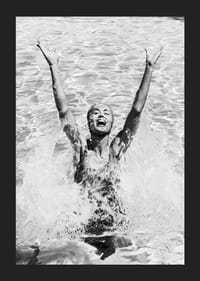 Schwarz-Weiß-Foto einer lächelnden Frau, die im Pool Wasser planscht-5