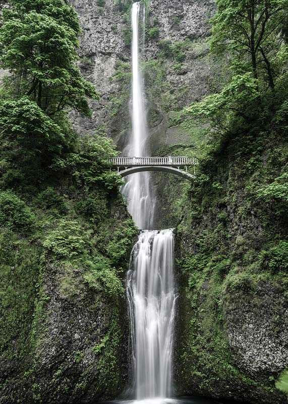 High waterfall with stone bridge, surrounded by greenery, photographic-12