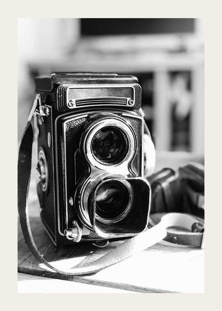 Black and white close-up of vintage two-lens analog camera on table-12
