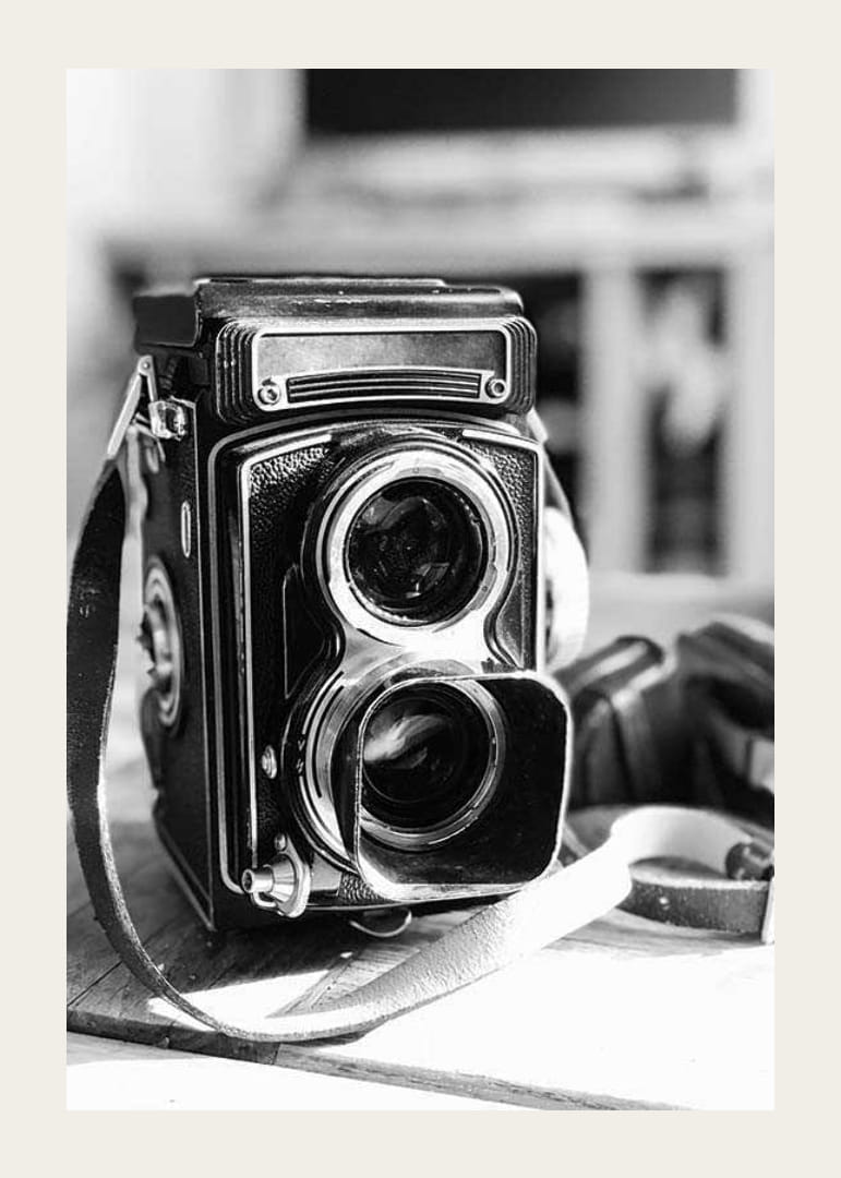 Black and white close-up of vintage two-eyed analog camera on table-12