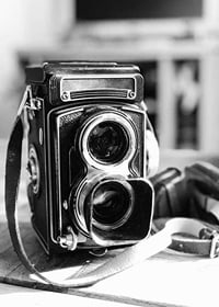 Black and white close-up of vintage two-lens analog camera on table-7
