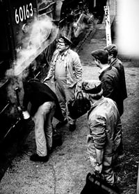 Black and white photo of men by steam locomotive on railway platform-7