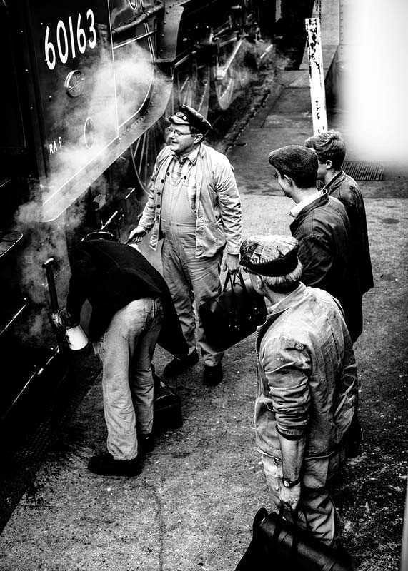 Black and white photo of men by steam locomotive on railway platform-12