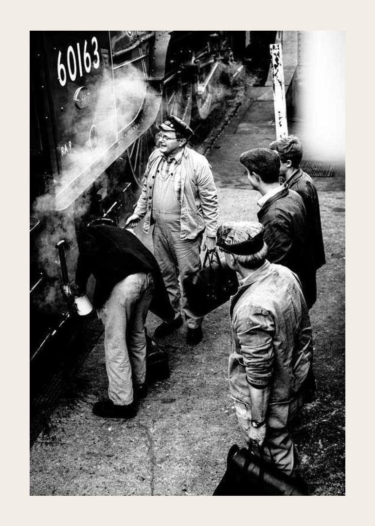 Czarno-białe zdjęcie mężczyzn przy lokomotywie parowej na peronie kolejowym-12