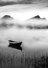 Black and white rowboat on foggy lake with mountains in the background-7