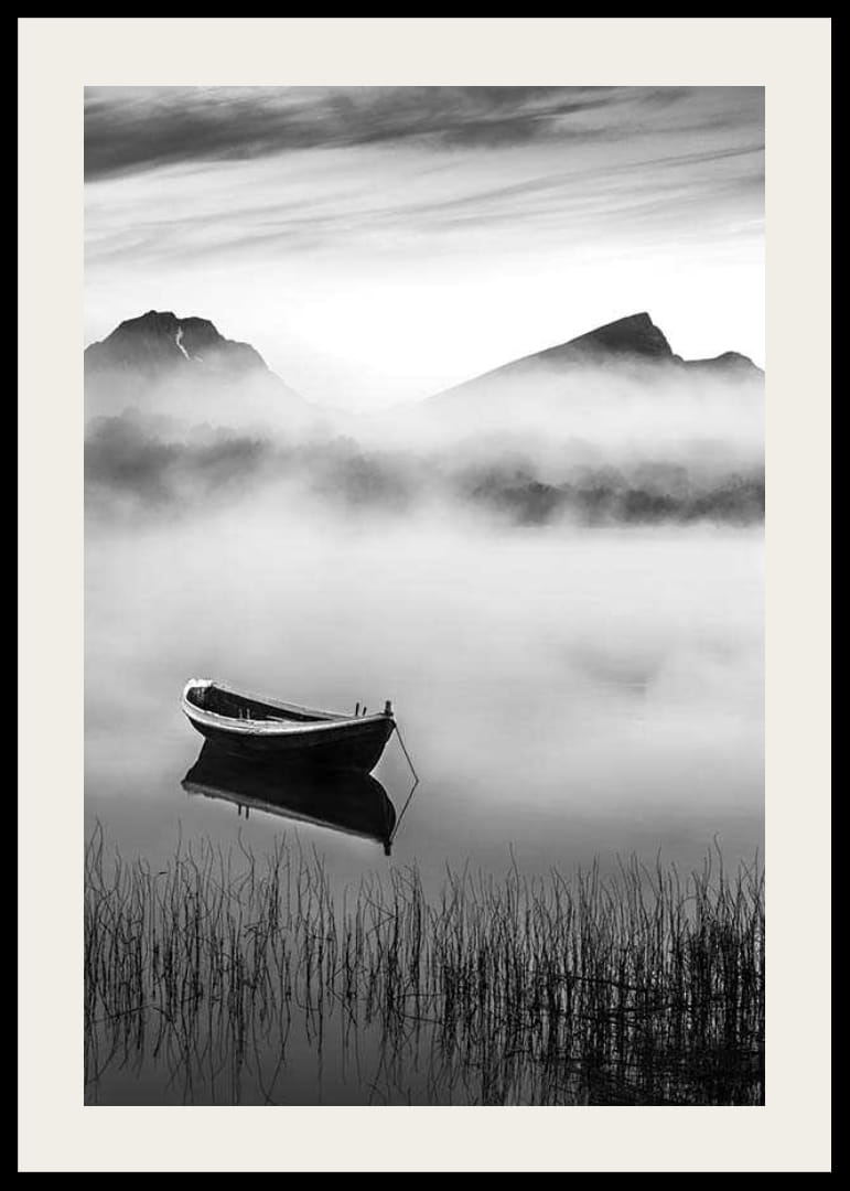 Barque noire et blanche sur un lac brumeux avec des montagnes en arrière-plan-12