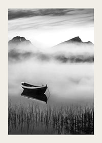 Black and white rowboat on foggy lake with mountains in the background-3