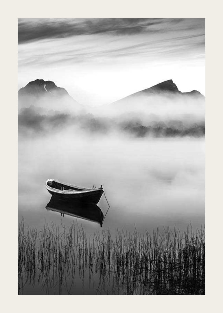 Black and white rowboat on foggy lake with mountains in the background-12