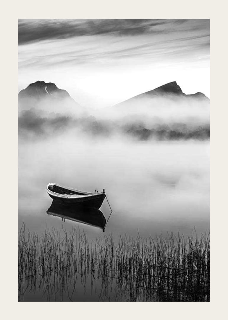 Barque noire et blanche sur un lac brumeux avec des montagnes en arrière-plan-12