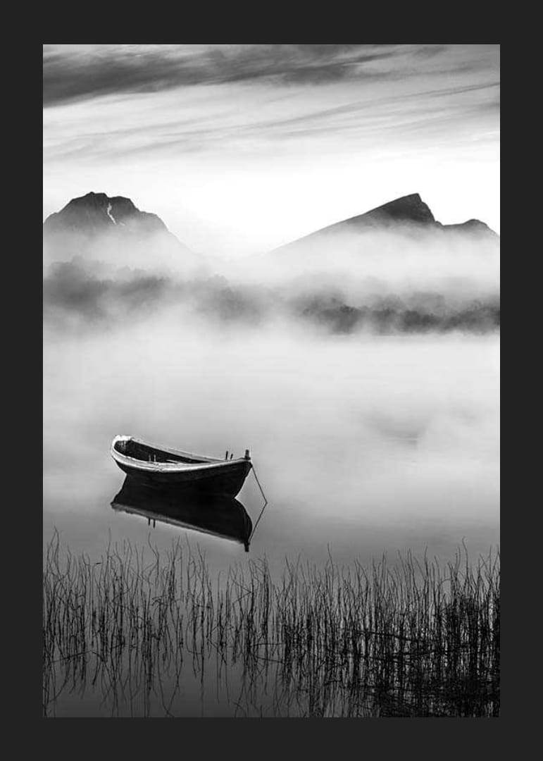Barque noire et blanche sur un lac brumeux avec des montagnes en arrière-plan-12