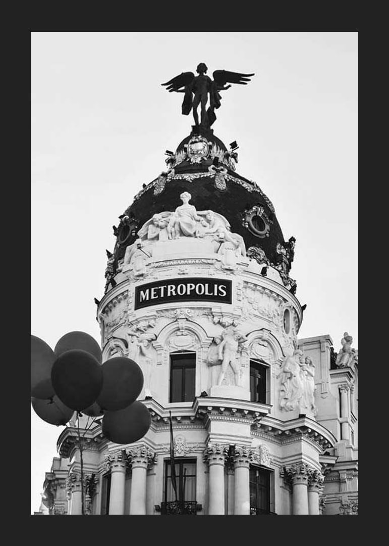 Black and white photo of the Metropolis building in Madrid with balloons-12