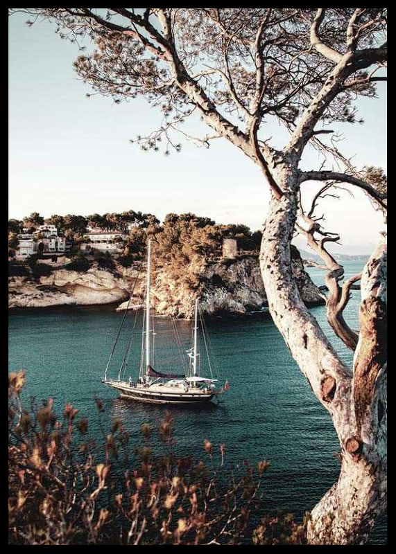 Photograph of sailboat in blue bay with cliffs and pine trees-12