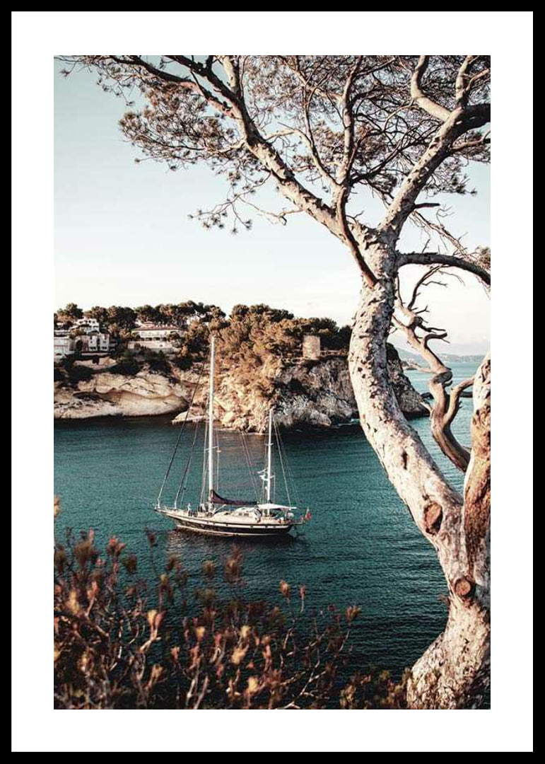 Photograph of sailboat in blue bay with cliffs and pine trees-12