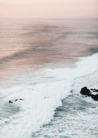 Photograph of ocean waves against coastal rocks in soft pink tones-7