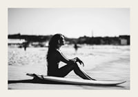 Black and white photo of woman on surfboard at sandy beach-3