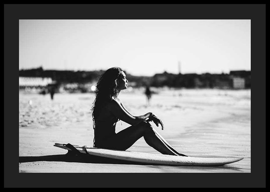 Black and white photo of woman on surfboard at sandy beach-12