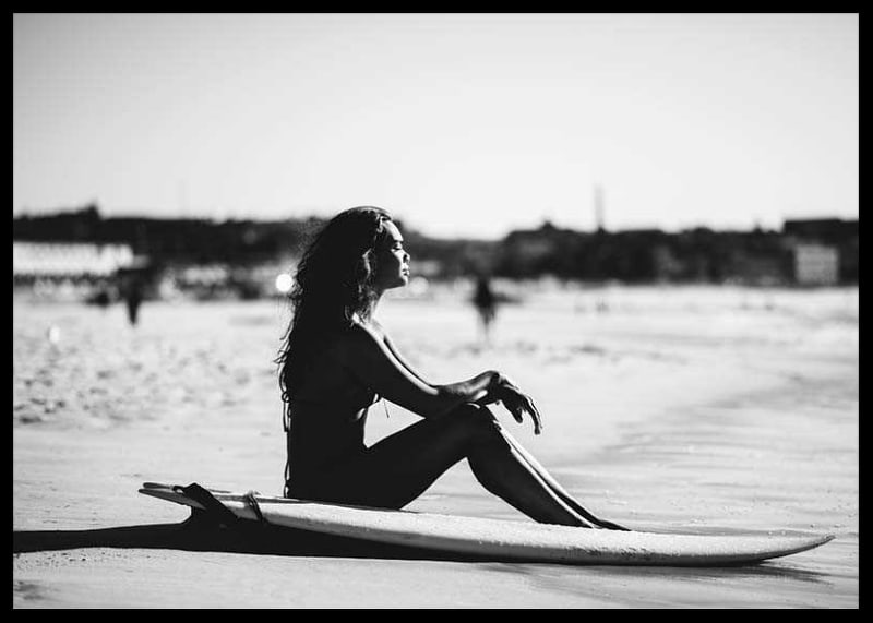 Black and white photo of woman on surfboard at sandy beach-12