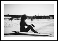 Black and white photo of woman on surfboard at sandy beach-0