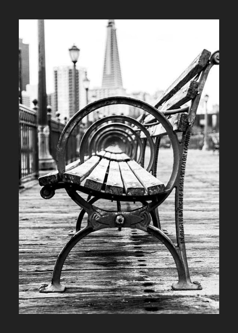 Čiernobiela fotografia lavičky v parku na drevenom móle s panorámou mesta-12