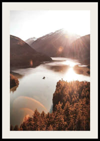 Fotografia di un lago illuminato dal sole e circondato da montagne boscose-2