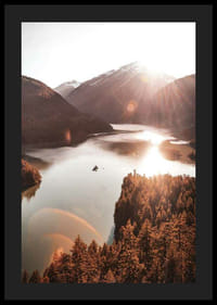 Fotografia di un lago illuminato dal sole e circondato da montagne boscose-4