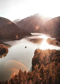 Photograph of sunlit lake surrounded by forested mountains-7