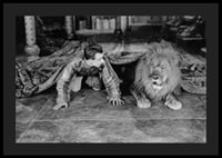 Black and white photograph of young man and lion on floor indoors-4