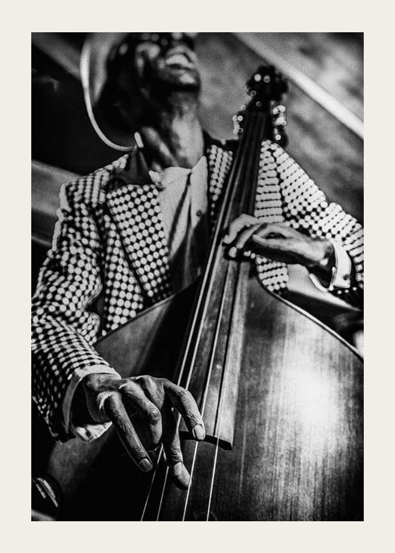 Black and white close-up of man in checkered jacket playing double bass-12