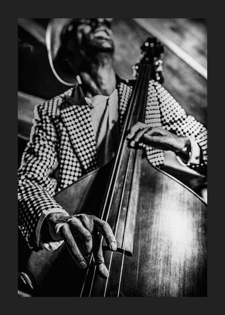 Primo piano in bianco e nero di un uomo con giacca a quadri che suona il contrabbasso-12